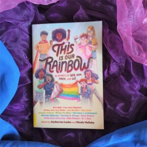 Das Buch "This is our Rainbow" liegt auf einem Hintergrund in den Farben der bisexuellen Pride-Flagge.