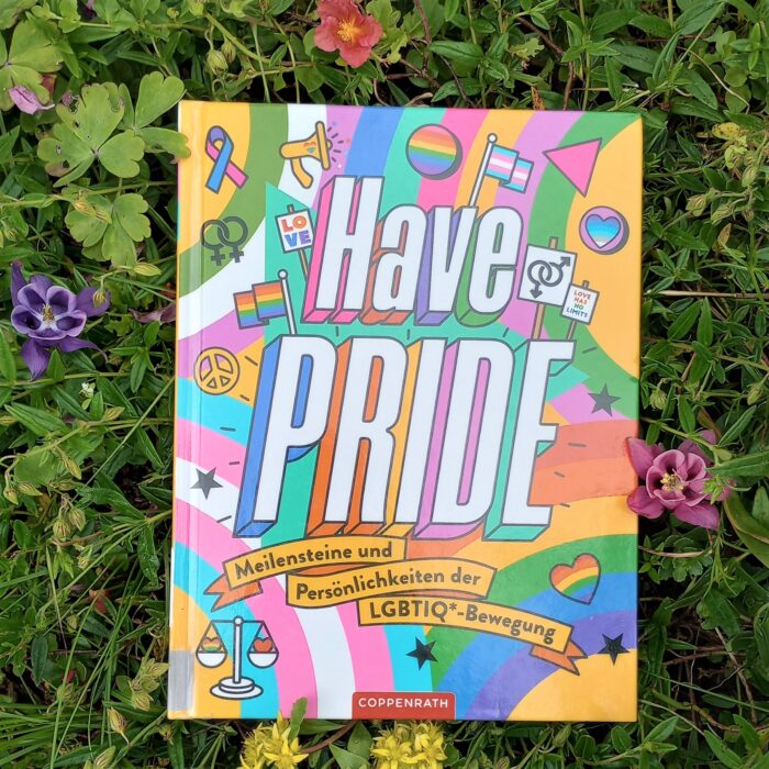 Ein Foto des Buchs "Have Pride" in einem Blumenbeet. Über das Foto führt ein Link zum Buch im Katalog der Stadtbücherei.