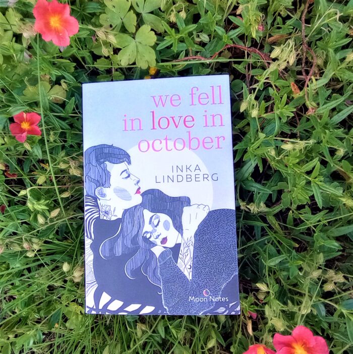 Ein Foto des Buchs "We fell in love in October" in einem Blumenbeet. Über das Foto führt ein Link zum Buch im Katalog der Stadtbücherei.