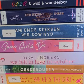 Ein Stapel queerer Bücher, die so angeordnet sind, dass sie einen Regenbogen bilden.