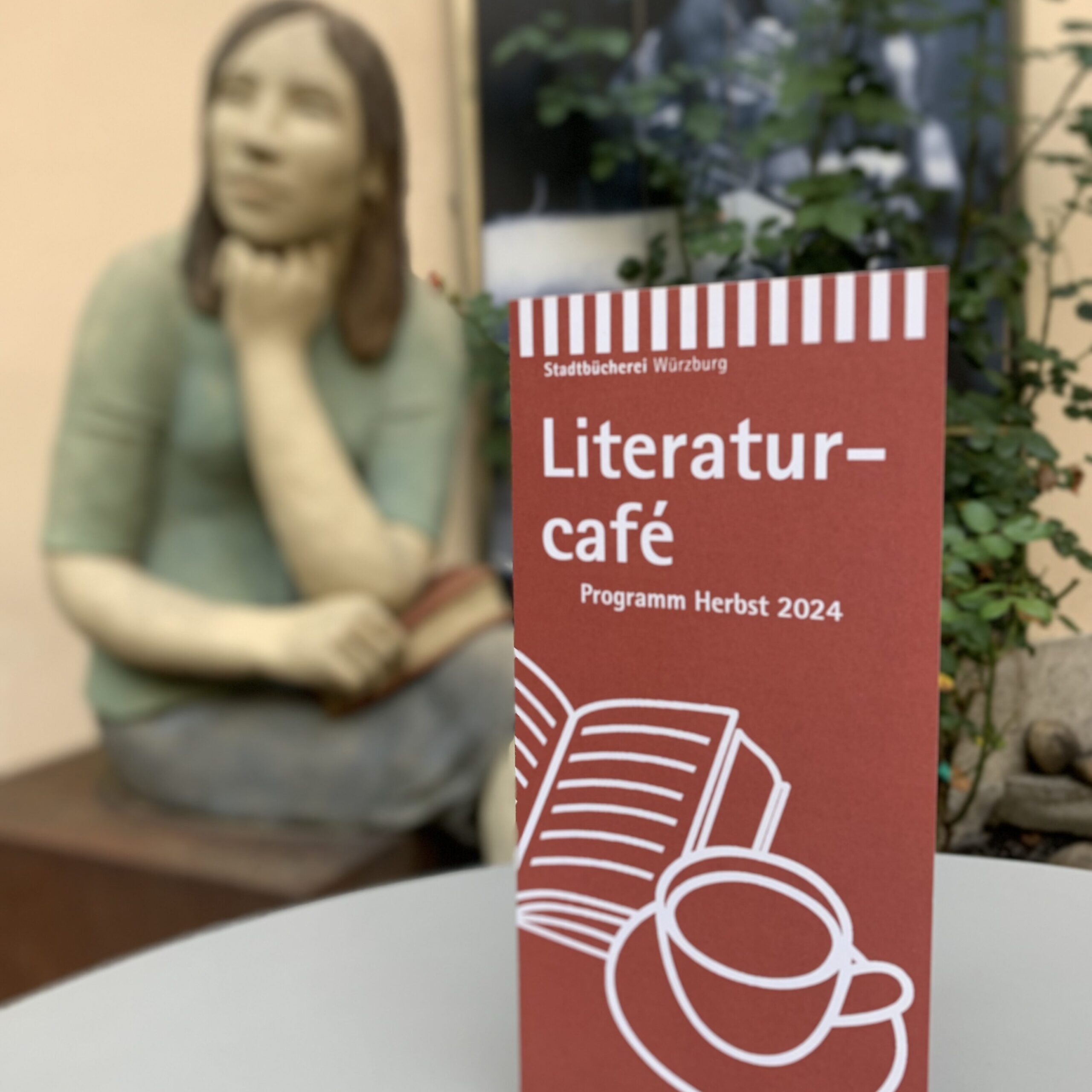 Ein Flyer mit dem Programm für das Literaturcafé steht im Lesegarten der Stadtbücherei.