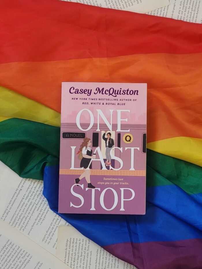 Das Buch "One last stop" liegt auf einer Pride Flagge.