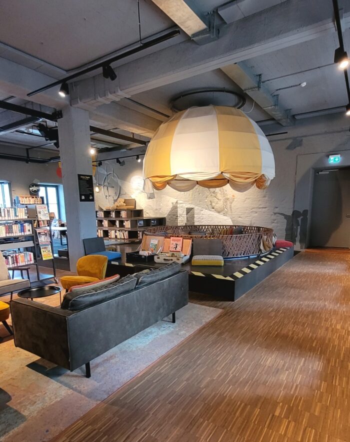 Ein Bild der Stadtteilbücherei Hubland. Darauf sieht man eine Sofaecke und einen großen Heißluftballon, in welchem die Familien gemeinsam lesen können. 