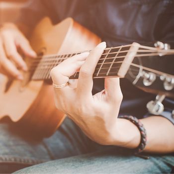 Eine Gitarre wird von zwei Händen gehalten.