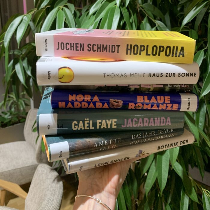 Eine Hand hält einen Stapel der bei "Bücher der Saison" vorgestellten Bücher.