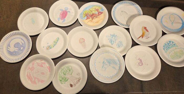 Zu sehen sind 15 weiße Pappteller, auf die verschiedene Tiere gemalt wurden.