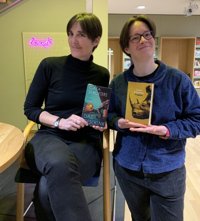 Zu sehen sind Autorin Gaea Schoeters und ihre Übersetzerin Lisa Mensing, die die beiden Bücher "Das Geschenk" und "Trophäe" halten.