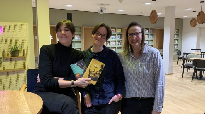 Zu sehen sind Autorin Gaea Schoeters, ihre Übersetzerin Lisa Mensing und eine Mitarbeiterin der Stadtbücherei mit den beiden Büchern "Das Geschenk" und "Trophäe".