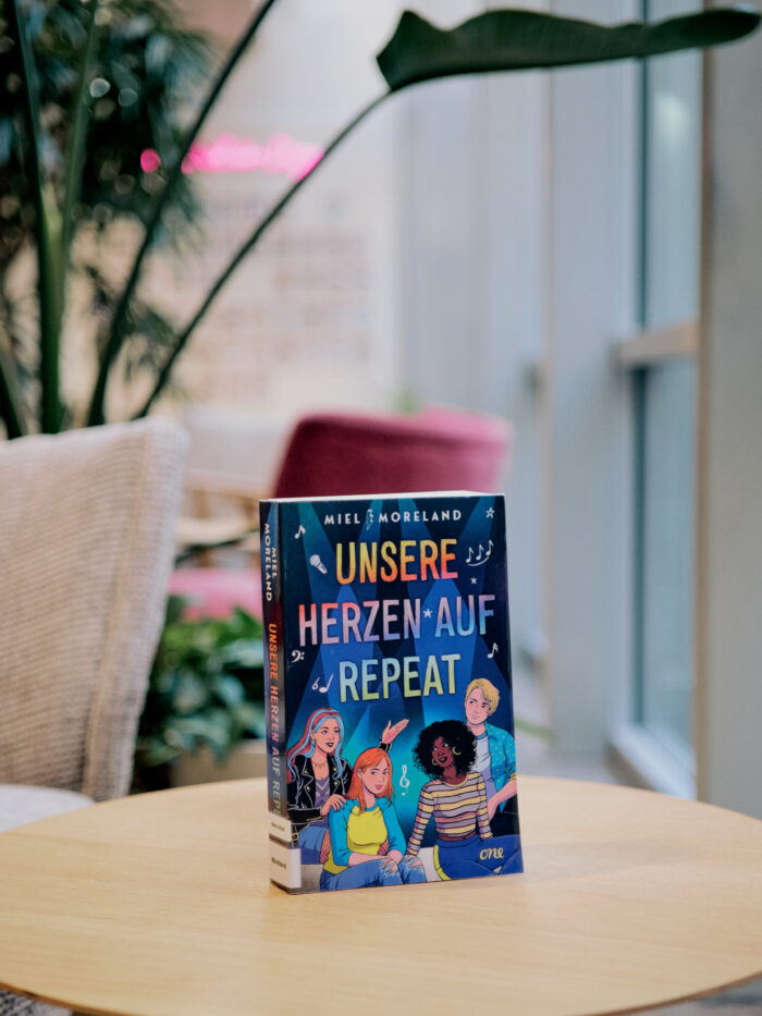 Zu sehen ist das Buch "Unsere Herzen auf Repeat" im Lesecafé der Stadtbücherei.