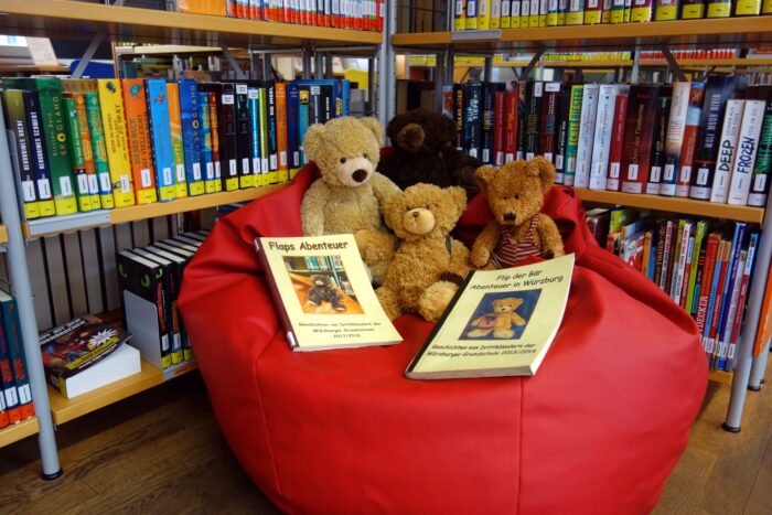 Zu sehen sind vier Teddybären mit Büchern, in denen ihre Abenteuer stehen.
