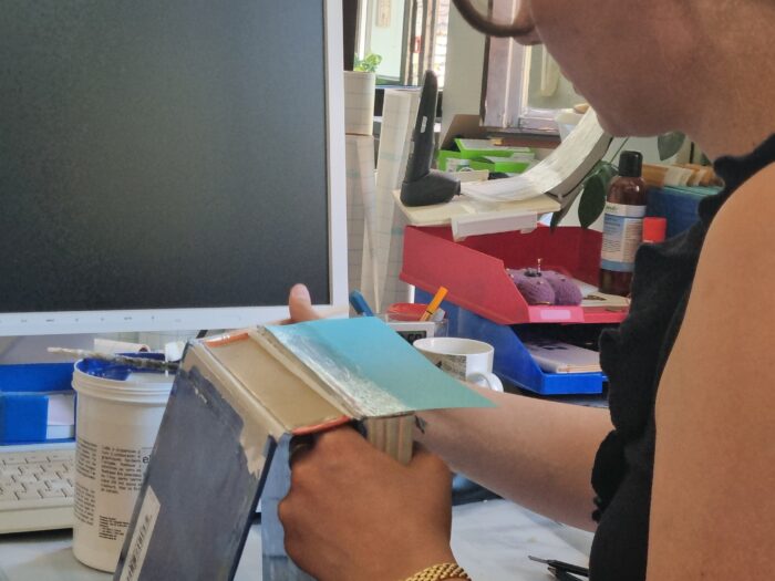 Zu sehen ist ein Mitarbeiter der Stadtbücherei, der einen kaputten Buchblock klebt.